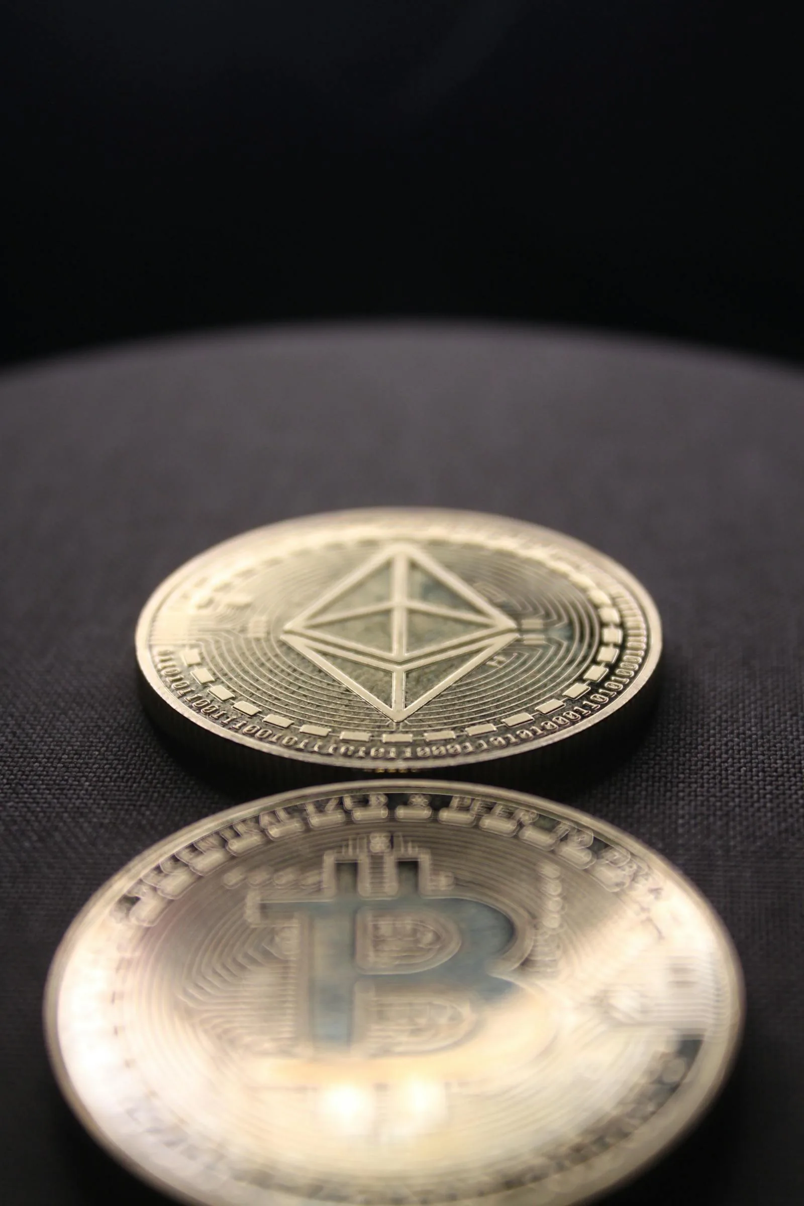 Đồng coin Ethereum đứng và Bitcoin nằm trên nền vải đen, minh họa so sánh gas fee giữa Ethereum và Bitcoin